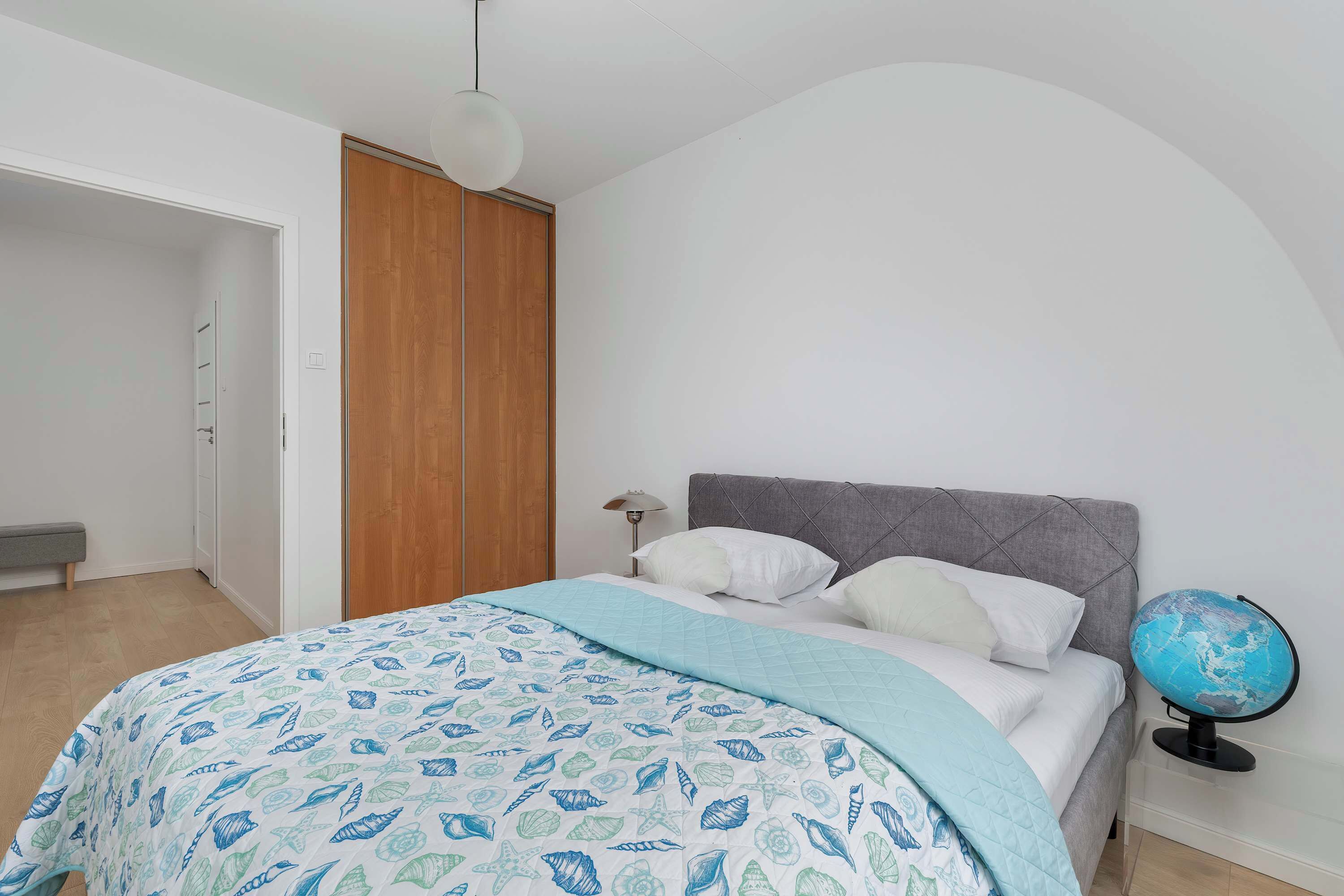 Een slaapkamer met een bed, een wereldbol, een kledingkast en een bankje.