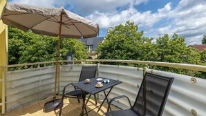 A balcony with a table, chairs, an umbrella, and a mop.