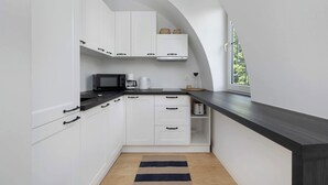 A modern kitchen with white cabinets, a black countertop, and a window providing natural light.