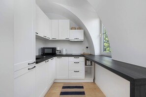 A modern kitchen with white cabinets, a black countertop, and a window providing natural light.
