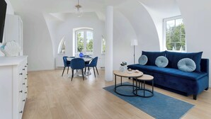 A modern loft with a dining area, a sofa, and a large window.