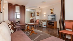 A living room with a sofa, a coffee table, a television, and a dining area with chairs and a table.