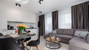A modern living room with a grey sofa, a coffee table, and a dining area with a table set for two.