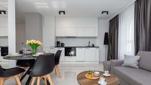 A modern living room with a grey sofa, a round coffee table, and a dining area with a table set for four.