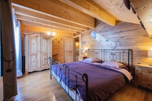 Ein Schlafzimmer mit Holzwänden, einem Bett, einem Kleiderschrank und einem an der Wand befestigten Snowboard.