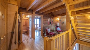 Een houten interieur met een trap, houten wanden en een zithoek met stoelen en kussens.