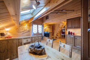 Ein Holzhütten-Innenraum mit Essbereich, Küche und einem Schlafzimmer im oberen Bereich mit Dachfenster.