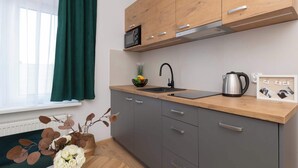 A modern kitchen with grey cabinets, a wooden countertop, a stainless steel kettle, and a black coffee maker.