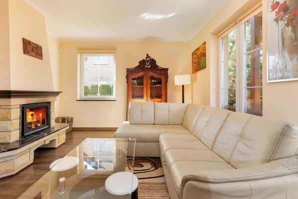 A living room with a fireplace, a sofa, a glass coffee table, and a cabinet.