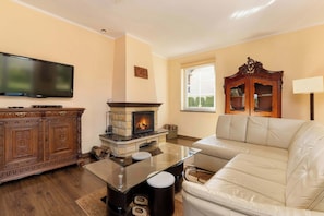 A living room with a fireplace, a flat-screen TV, a sofa, and a wooden cabinet.