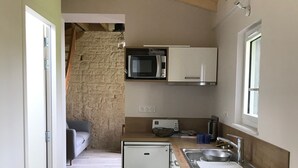 A compact kitchen with a microwave, sink, and washing machine.