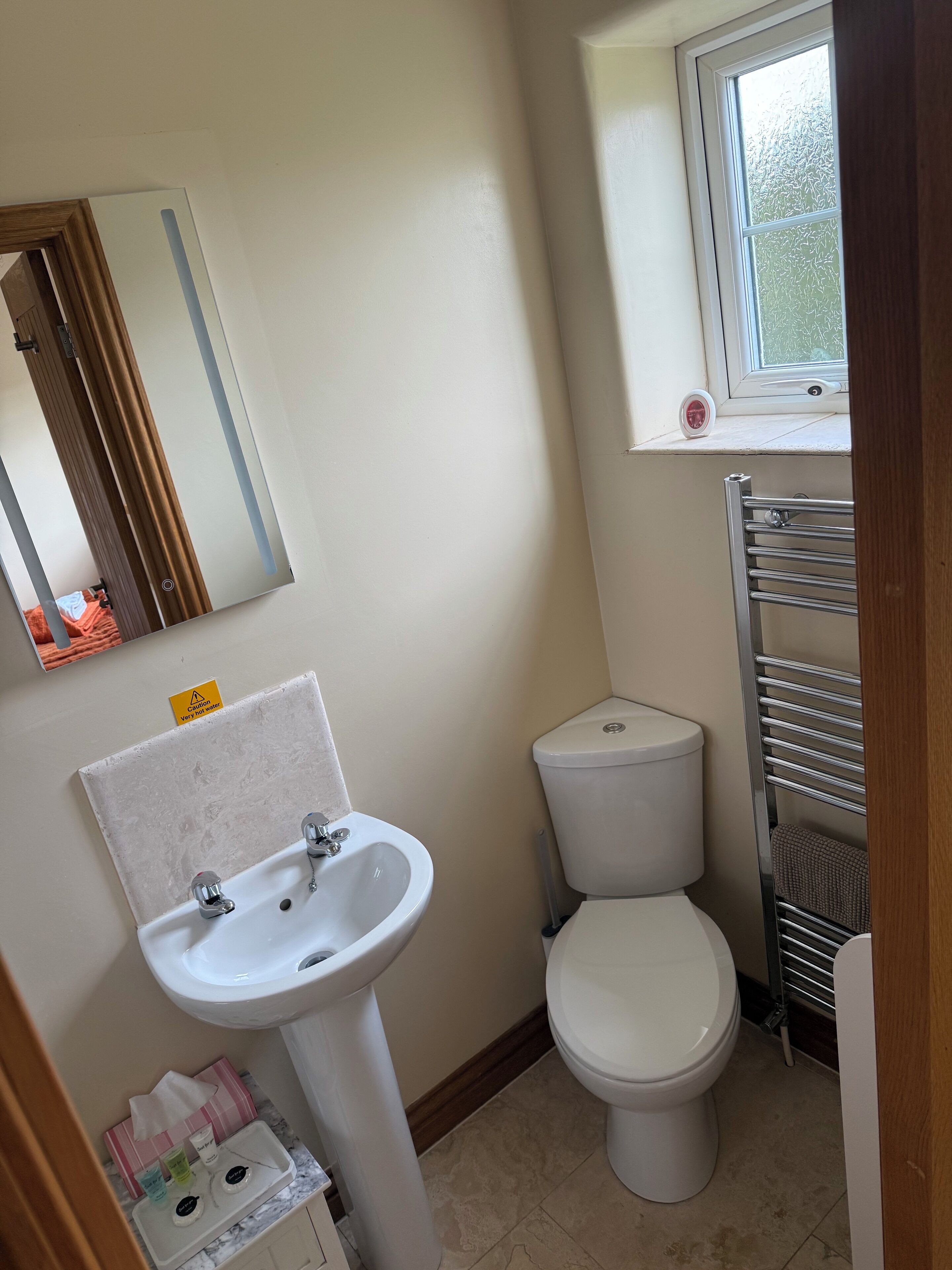 A bathroom with a white sink, toilet, and a window above the toilet.