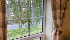 A room with a window overlooking a grassy area and a road. There is a wooden shelf with a figurine of a bird and a rabbit. - the Star Inn (Weaverthorpe)