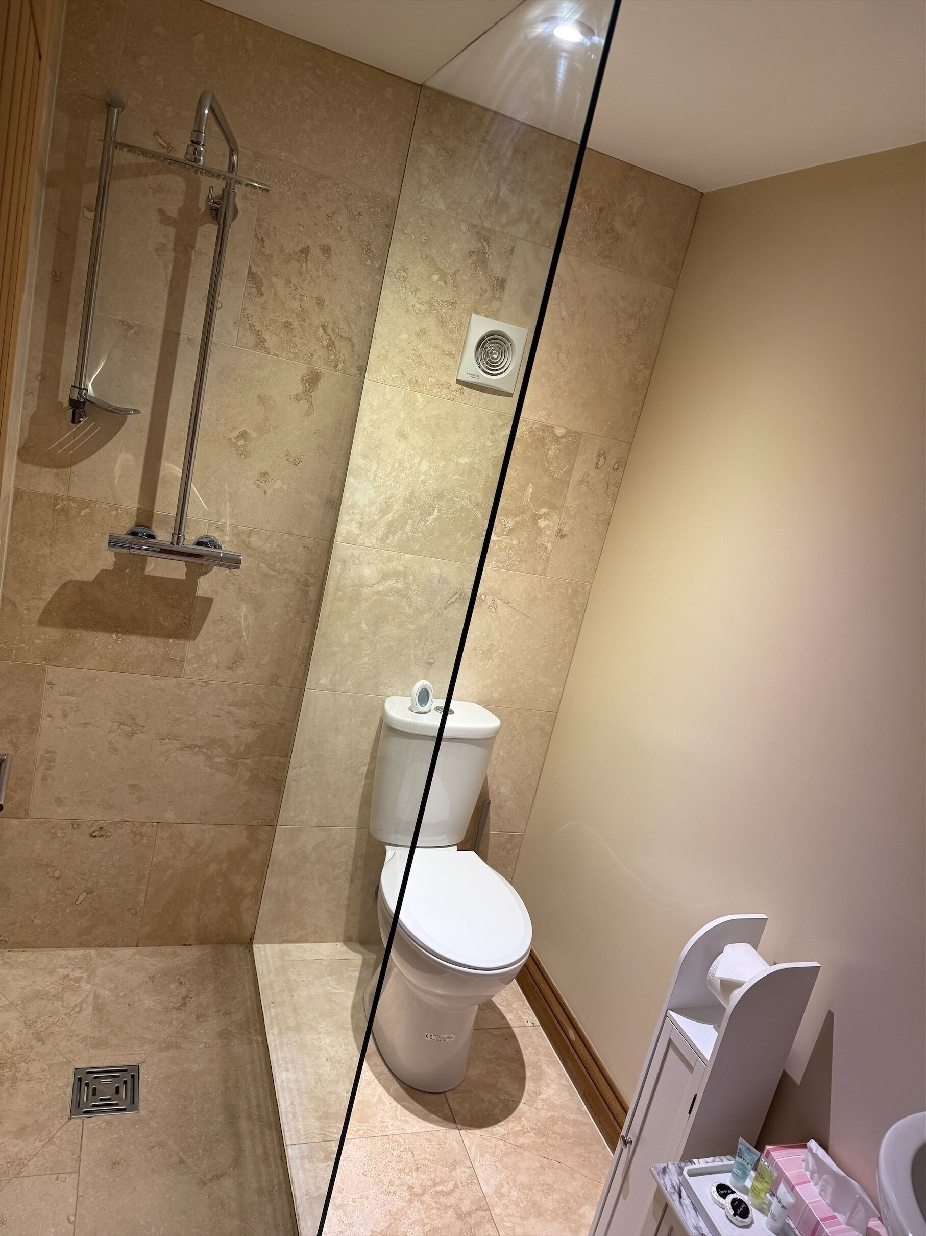 A bathroom with a shower, toilet, and a vanity with toiletries.