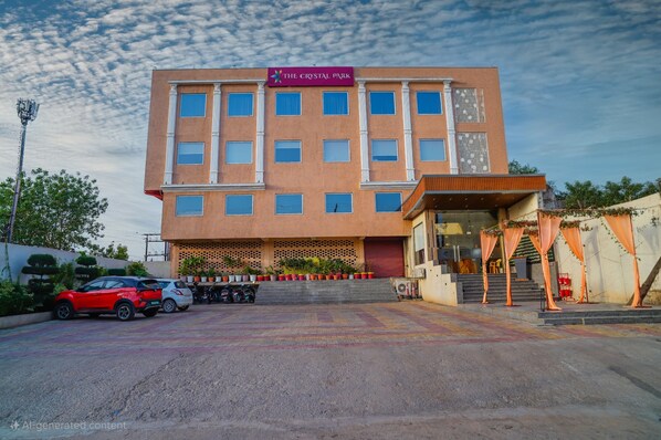A multi-story hotel named "The Crystal Park" with a modern facade, a covered entrance, and a parking area with several cars. - Hotel The crystal Park  (Gwalior)