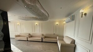 Un salón comedor amplio con una lámpara moderna, un sofá seccional grande y un equipo de aire acondicionado instalado en la pared.