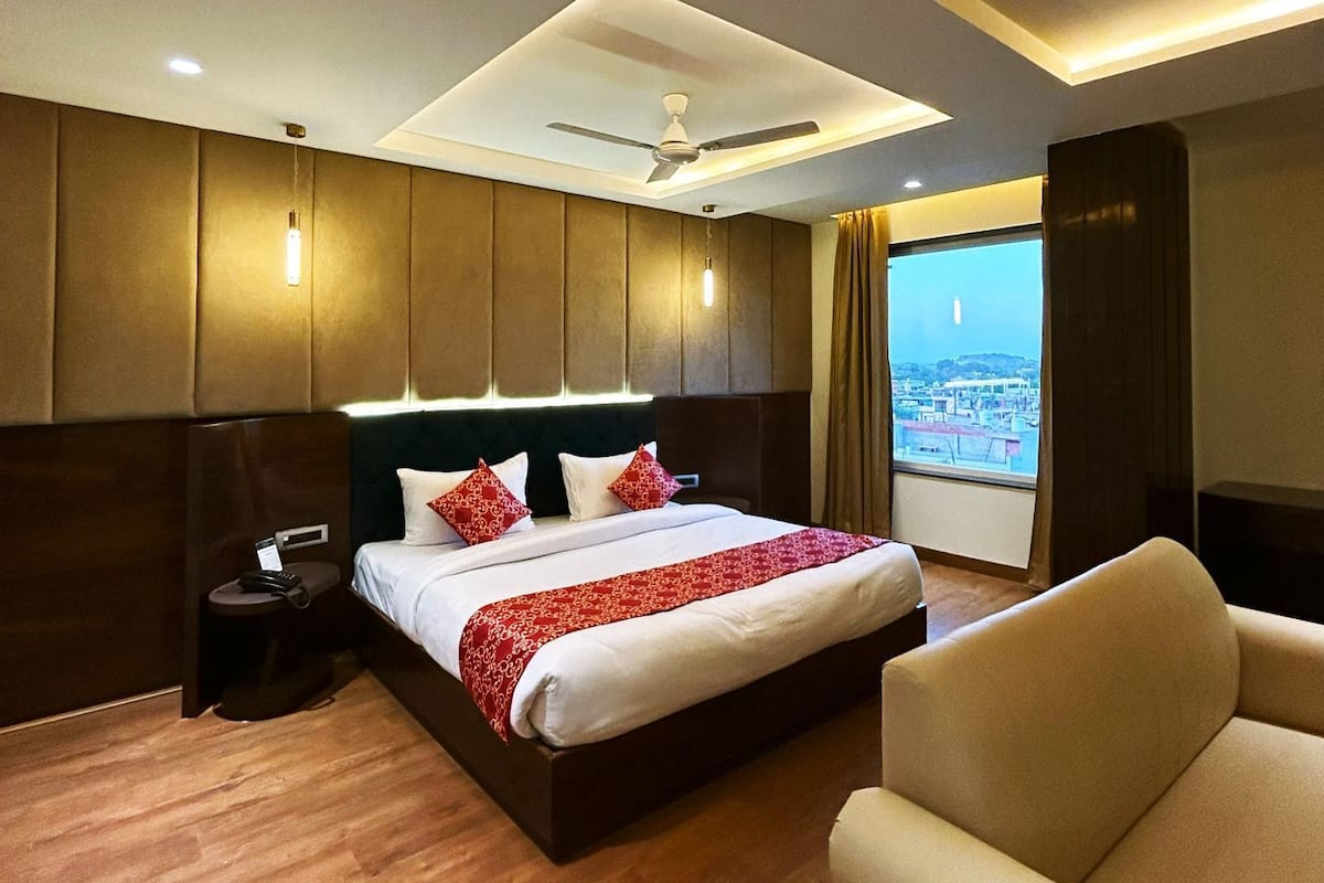 Ein Hotelzimmer mit einem großen Bett, einem Deckenventilator und Blick auf eine Stadtlandschaft durch das Fenster.