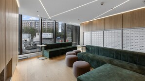 A modern waiting area with a green sofa, ottomans, and a wall of lockers.