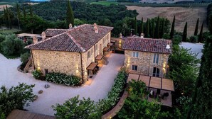A stone house with a courtyard, surrounded by greenery and hills. - One Belvedere Tuscany (Poggibonsi)