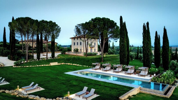 A poolside area with lounge chairs and a large pool, surrounded by well-manicured lawns and tall cypress trees. - One Belvedere Tuscany (Poggibonsi)