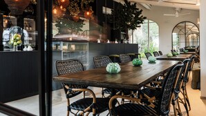 A modern dining area with a long wooden table, black and white wicker chairs, and green decorative vases. - One Belvedere Tuscany (Poggibonsi)