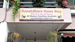 A two-story building with a sign for Kanakdhara Home Stay, offering both AC and non-AC rooms.