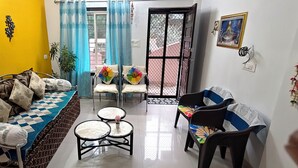 A living room with a sofa, chairs, a small table, and a decorative plant.
