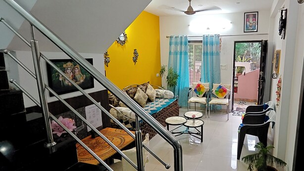 A living room with a sofa, chairs, a small table, and a staircase.