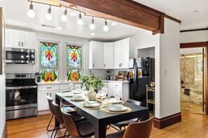 Una cocina moderna con armarios blancos, electrodomésticos de acero inoxidable y ventanas con vitrales.