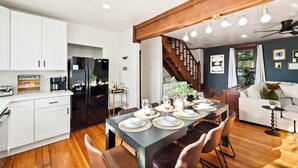 A modern kitchen with white cabinets, a black refrigerator, and a dining area with a wooden table set for six. - Top 2 Floors Historic Mansion,Game Room,City Views (San Diego)