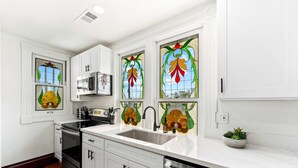 A modern kitchen with white cabinets, a stainless steel sink, a microwave, and a dishwasher. - Top 2 Floors Historic Mansion,Game Room,City Views (San Diego)