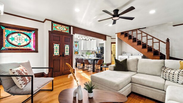 A modern living room with a sofa, chair, and coffee table, a staircase, and a kitchen in the background. - Top 2 Floors Historic Mansion,Game Room,City Views (San Diego)