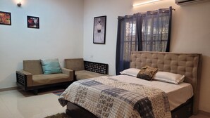 Quarto com cama, dois sofás, tapete e obras de arte nas paredes.