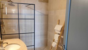 Un baño con un lavamanos grande, una cabina de ducha de vidrio y una escalera de madera.