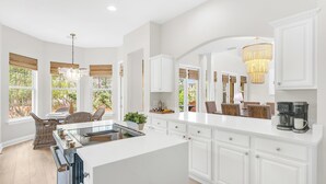 A spacious kitchen with white cabinetry, a large island, and a chandelier. - Southern Breeze Family Home 2 Pools Private Beach (Gulf Shores)