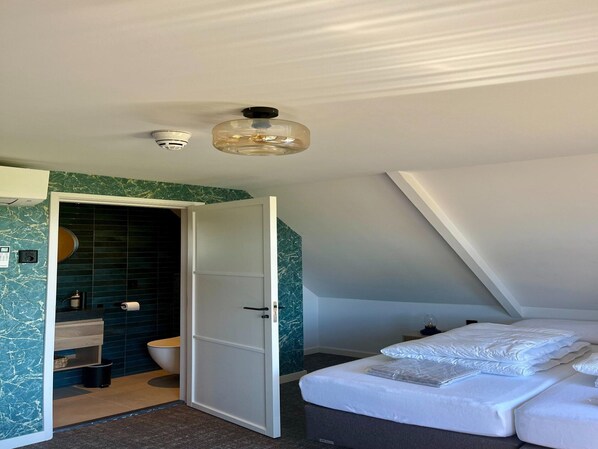 Une chambre à coucher moderne avec un lit, une salle de bain avec des toilettes et un lavabo, et un luminaire au plafond.