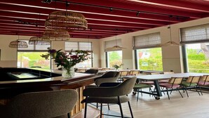 A restaurant with a high ceiling, exposed beams, and large windows offering views of greenery. - Group Accommodation for 40 Guests (Scherpenzeel)
