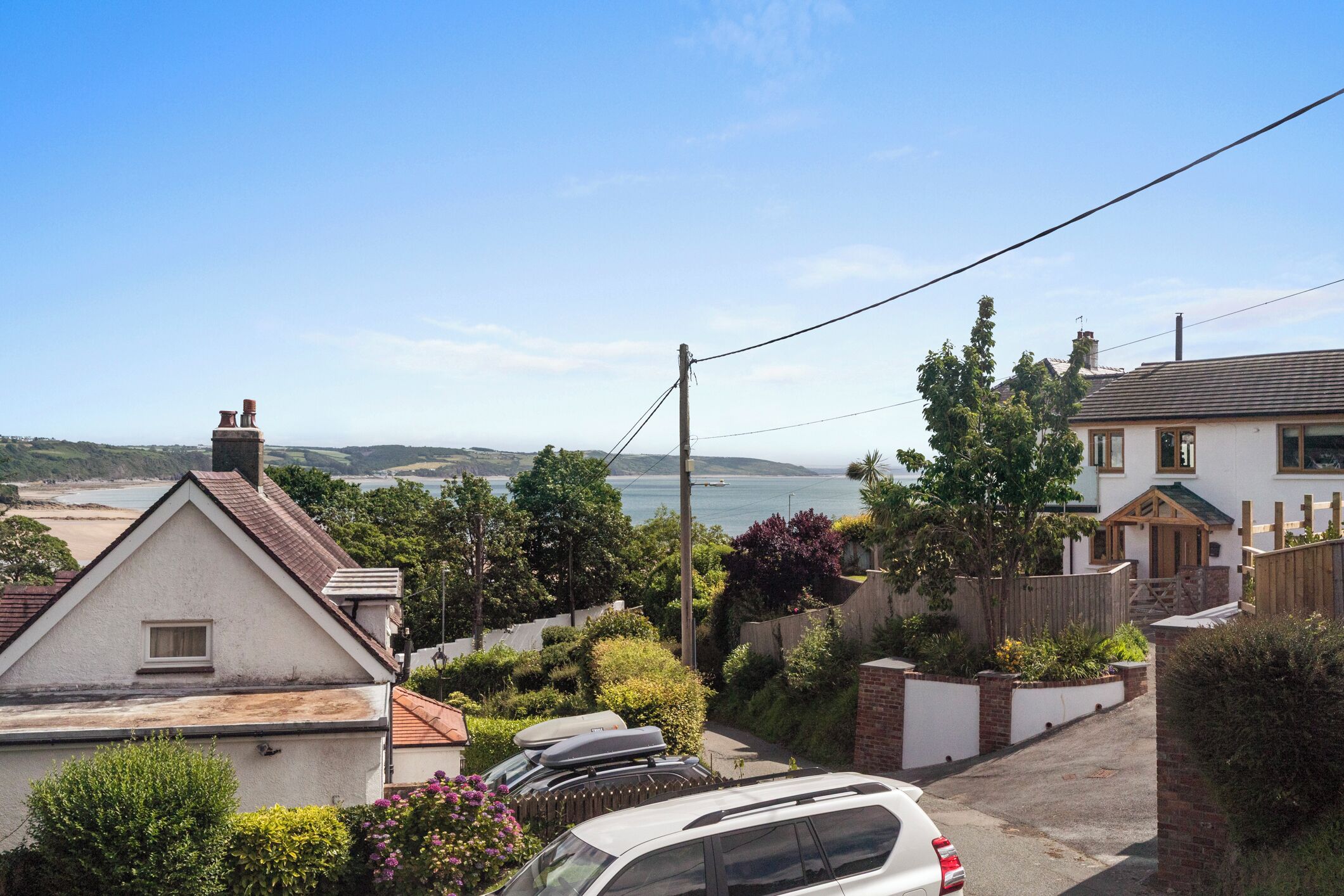 A residential area with houses, a car, and a view of the sea.