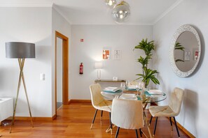 A dining area with a round table, chairs, a lamp, and a mirror on the wall.