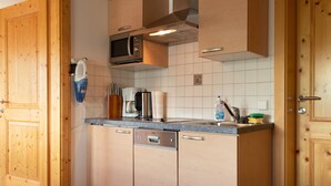 A kitchen with wooden cabinets, a microwave, a coffee maker, and a dishwasher. - Apartment 'Almrausch' with Shared Terrace, Balcony and Wi-Fi (Wagrain)