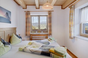 A bedroom with a bed, a window with curtains, a wooden headboard, and a painting on the wall. - Apartment 'Almrausch' with Shared Terrace, Balcony and Wi-Fi (Wagrain)