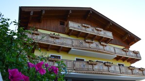 A multi-story building with wooden balconies, a yellow facade, and a door with a sign. - Apartment 'Almrausch' with Shared Terrace, Balcony and Wi-Fi (Wagrain)