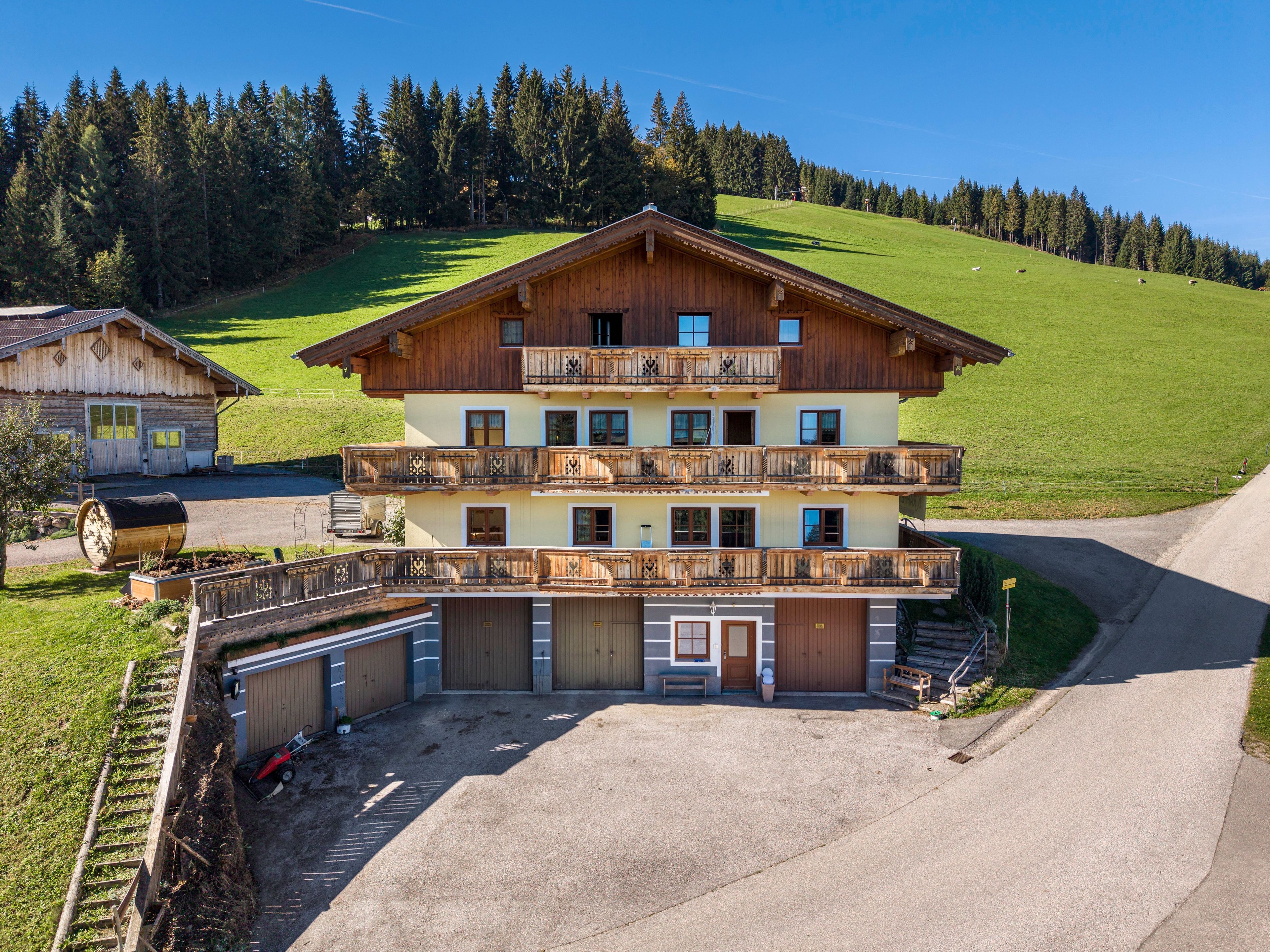 A multi-story wooden building with balconies, a garage, and a paved driveway.