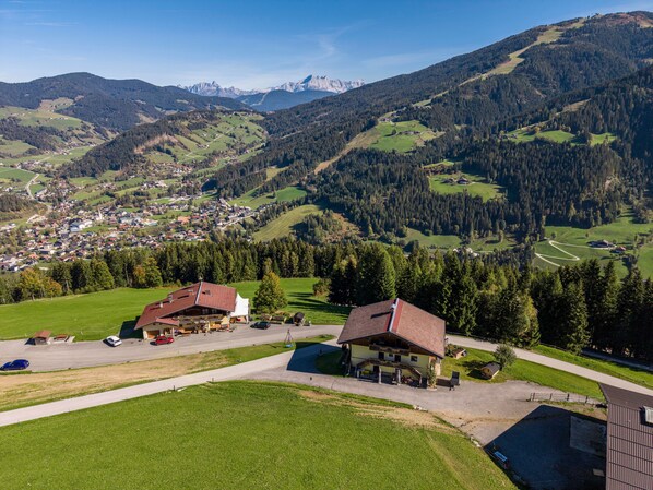 A rural landscape with a small town, green fields, and a mountain range in the background.