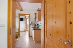 A wooden door leading into a kitchen with a tiled floor, a sink, and a stove. - Apartment 'Almrausch' with Shared Terrace, Balcony and Wi-Fi (Wagrain)