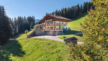 A multi-story hotel with a sloped roof, located on a hillside with a view of a forest.