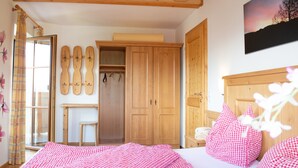 A bedroom with a bed, a wooden wardrobe, a small table, and a window with curtains. - Apartment 'Almrausch' with Shared Terrace, Balcony and Wi-Fi (Wagrain)