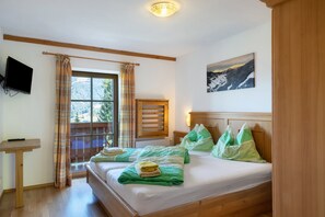 Habitación de hotel con cama, escritorio, televisor y ventana con cortinas.