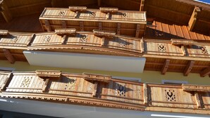 Ein mehrgeschossiges Gebäude mit hölzernen Balkonen, verziert mit aufwendungen Schnitzereien.