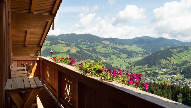 Ein Holzbalkon mit Blick auf grüne Hügel und eine Stadt.